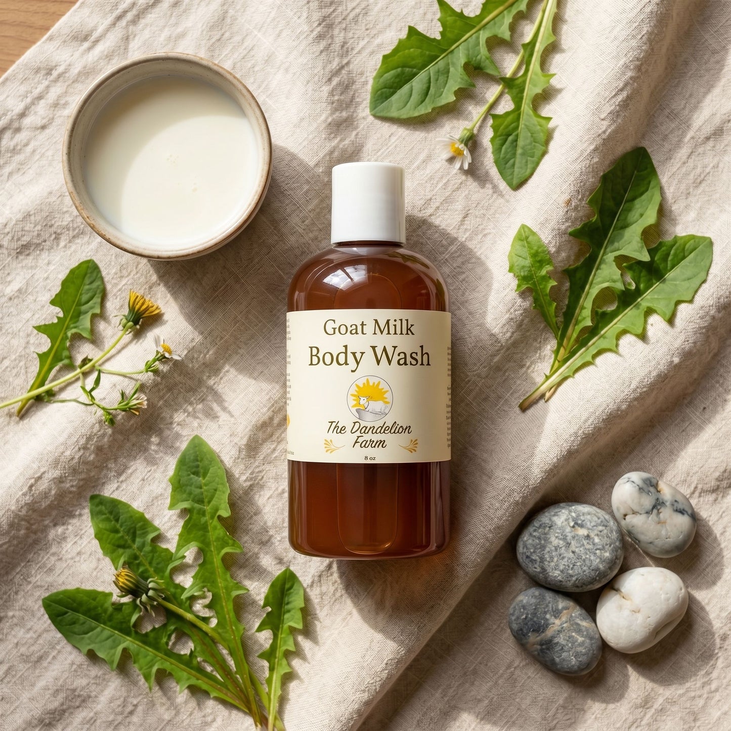 Overhead flat lay of goats milk body wash surrounded by natural ingredients like goat’s milk, leaves, and stones, under warm natural light.