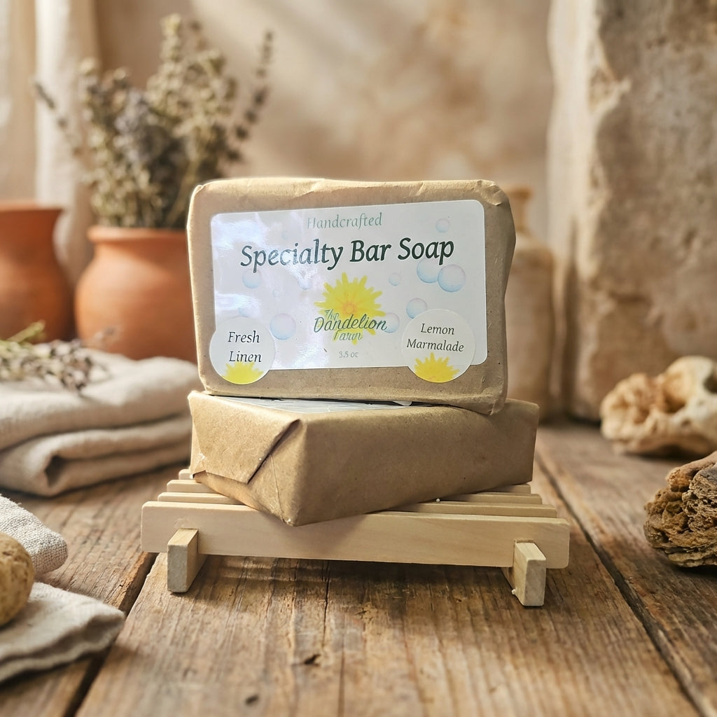 Display the 'Specialty Bar Soap' collection in a rustic, Mediterranean-inspired setting, with the soaps stacked artistically on a wooden tray. Use warm, diffused daylight to accentuate the rich, natural hues of the ingredients—coffee's deep browns, wine's 
