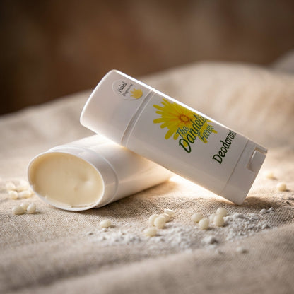A cinematic, close-up shot of the natural deodorant lying horizontally on an elegant, textured linen cloth, captured with a 100mm macro lens. The scene is lit with rim lighting to accentuate the contours of the deodorant, creating a luminous edge glow that