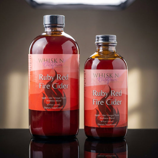 Capture a high-resolution, studio shot of 'Ruby Red Fire Cider' placed on a sleek, reflective black surface under softbox lighting which creates gentle highlights and shadows, emphasizing the vibrant ruby-red hue of the tonic. The scene is shot from a slig