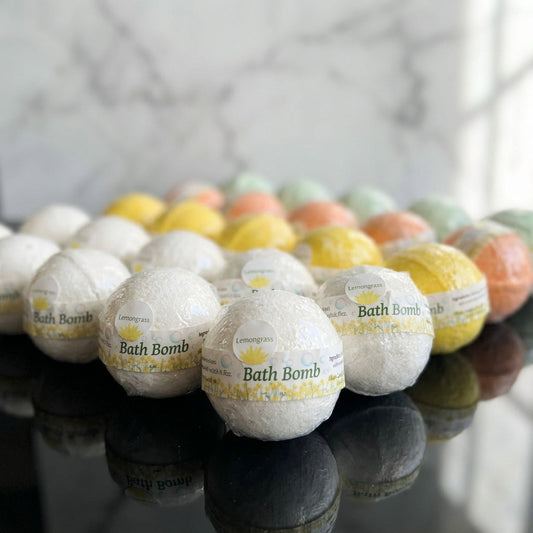 A high-resolution studio shot of a collection of vibrant bath bombs arranged on a sleek, reflective black surface, illuminated by softbox lighting that highlights their textured, crystalline surfaces and colorful swirls. The background features a softly bl
