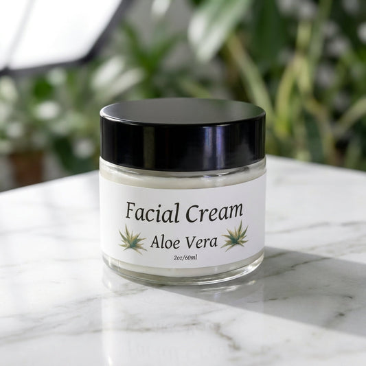 A close-up shot of the Aloe Vera Facial Cream jar, expertly lit with softbox lighting to highlight the creamy texture and natural green hue of the product. The scene is set on a clean, white marble surface with subtle reflections, emphasizing purity and cl