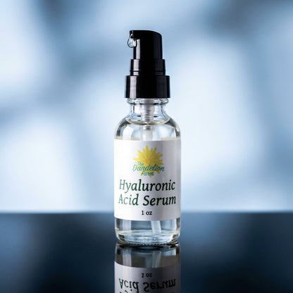 A sleek, modern still-life composition of the Hyaluronic Acid Serum bottle, illuminated with softbox lighting to highlight the transparency and smooth texture of the glass container. The scene is set on a reflective black surface, with subtle reflections e