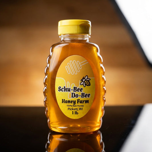 A close-up shot of the 'Schu-Bee Do-Bee Honey' jar, illuminated with softbox studio lighting to emphasize the golden, viscous texture of the honey. The camera is set at a slight downward angle with a macro lens focus, capturing the intricate details of the