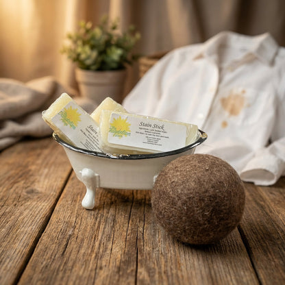An elegant lifestyle scene featuring the Stain Stick on a rustic wooden table, with a freshly stained shirt partially visible in the background. Warm, HDR studio lighting creates a cozy yet professional ambience. The camera employs a 85mm portrait lens wit
