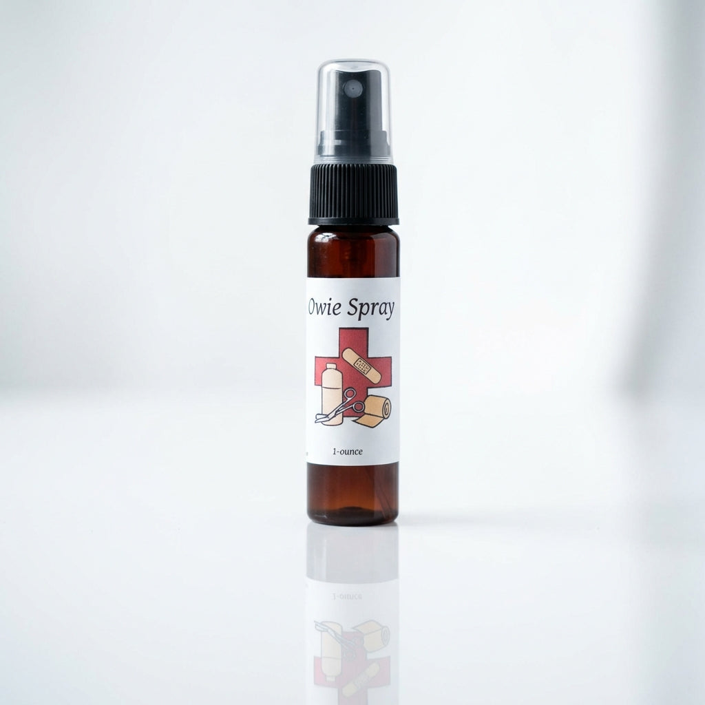 A close-up shot of Owie Spray standing upright on a sleek, reflective white surface in a professional studio setting. The lighting is softbox diffused daylight, emphasizing the clear, clean design of the spray bottle with detailed visibility of the label s