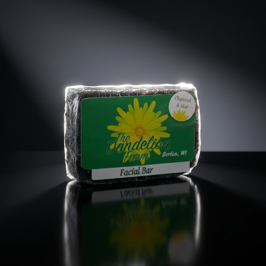 A clean, minimalist studio setup with a single facial bar placed on a reflective black surface, lit by a rim light that creates a striking halo effect around the soap. The focus is sharp, highlighting the soap’s textured surface and intricate natural ingre