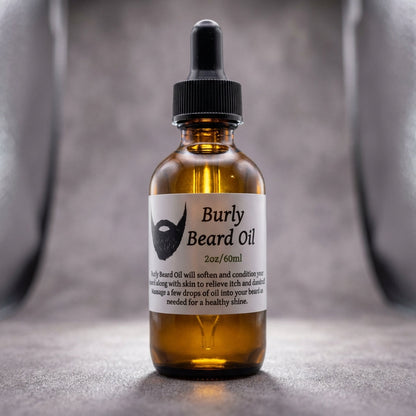 Close-up macro shot of the 'Burly Beard Oil' bottle, expertly lit with rim lighting to accentuate its transparent glass and golden oil inside, set against a textured, matte grey background that contrasts with the shiny surface of the product. The image cap