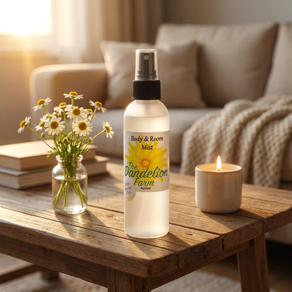Illustrate a cozy, inviting living room scene at sunset, with the 'Body & Room Mist' prominently placed on a rustic wooden coffee table. Warm, diffused daylight spills into the room, creating a calm, golden glow. Use a macro lens (100mm) to focus tightly o