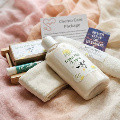 An artistic, close-up product shot of the 'Chemo Care Package' items artistically arranged on a delicate, textured fabric backdrop in soft pastel shades to evoke tenderness. The shot is taken with a macro lens at a 100mm focal length, focusing sharply on t