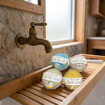 Small goat’s milk bath bombs resting on a bamboo tray next to vintage brass faucet in a warm natural stone and wooden bathroom.