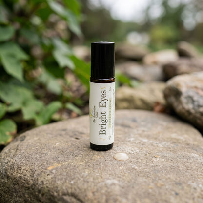 Close-up of 'Bright Eyes' serum bottle on natural stone countertop outdoors, illuminated by diffused daylight.