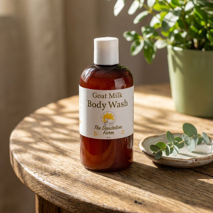 Stylized side view of goats milk body wash on a rustic wooden table with sunlight casting shadows and emphasizing natural qualities.