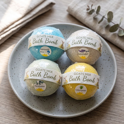 Close-up of handcrafted goat’s milk bath bombs with pastel colors on a ceramic dish, highlighting their smooth texture and handcrafted details.