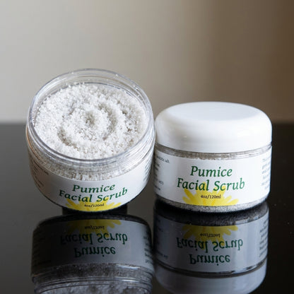 Close-up of a small pumice facial scrub with granules and oils on a reflective black surface.